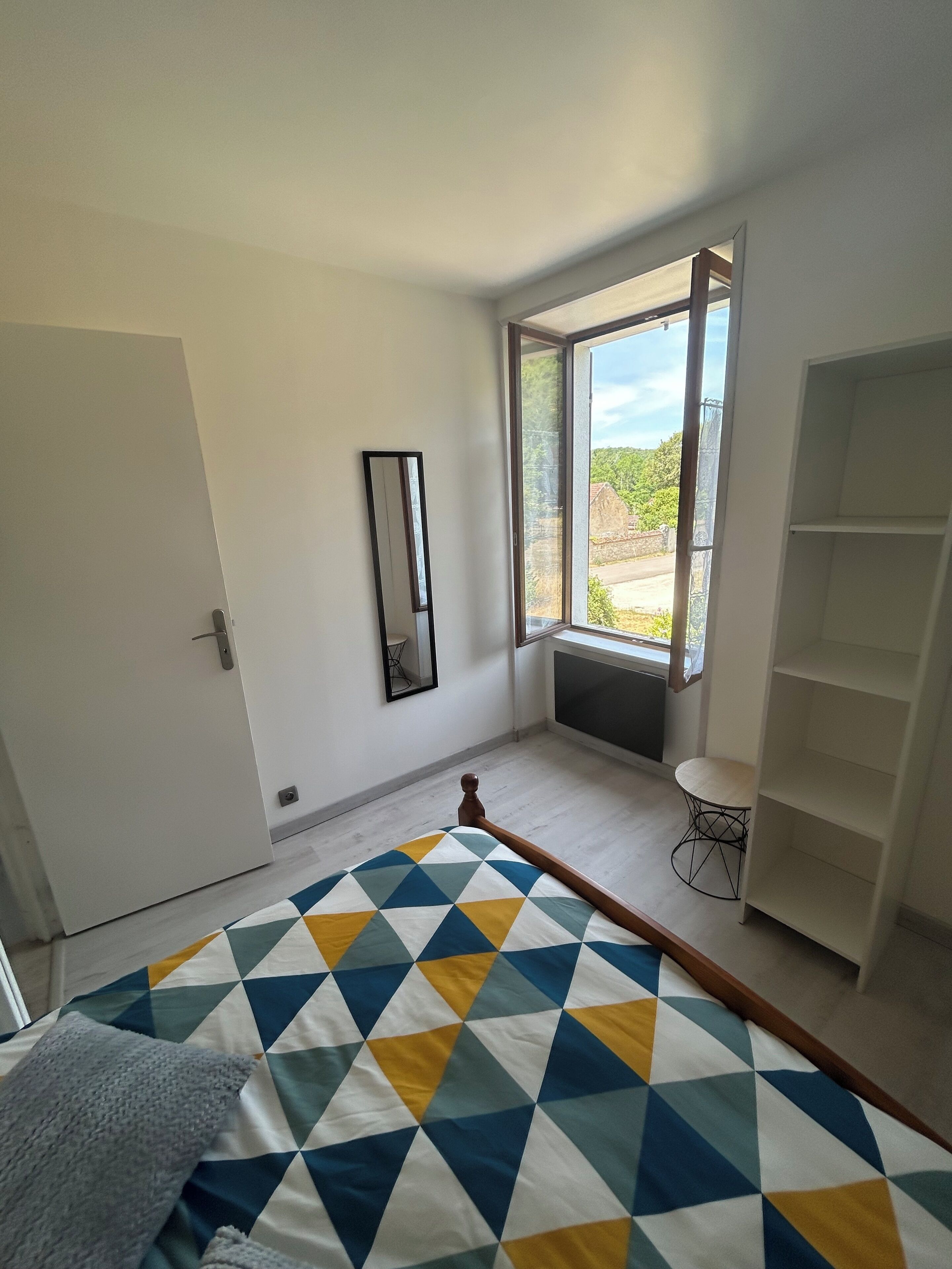 Una camera da letto con un letto, una finestra, uno specchio e un armadio.