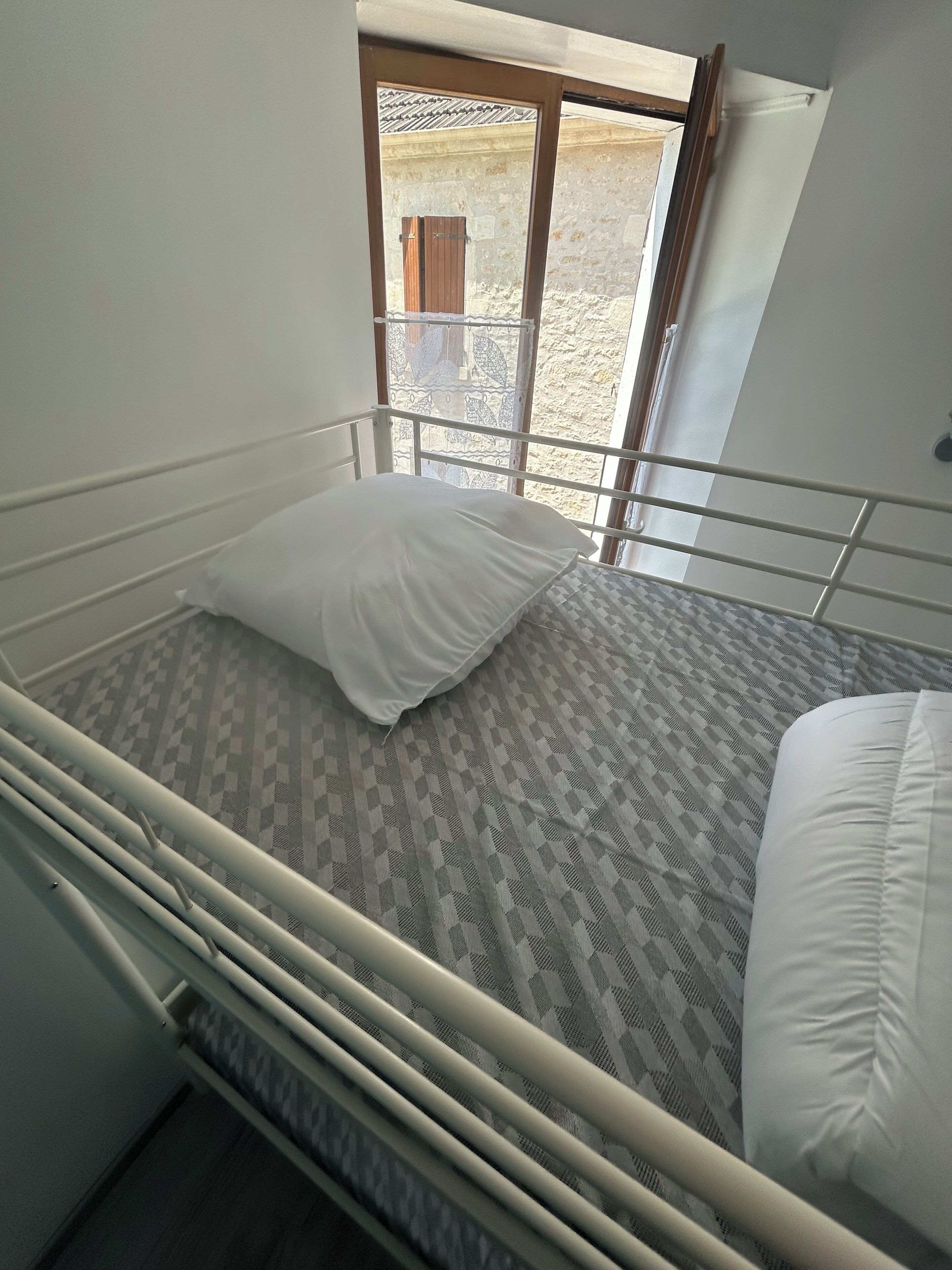 Ein Einzelbett mit einem gemusterten Matratze, einem weißen Kopfkissen und einem Metallgestell.
