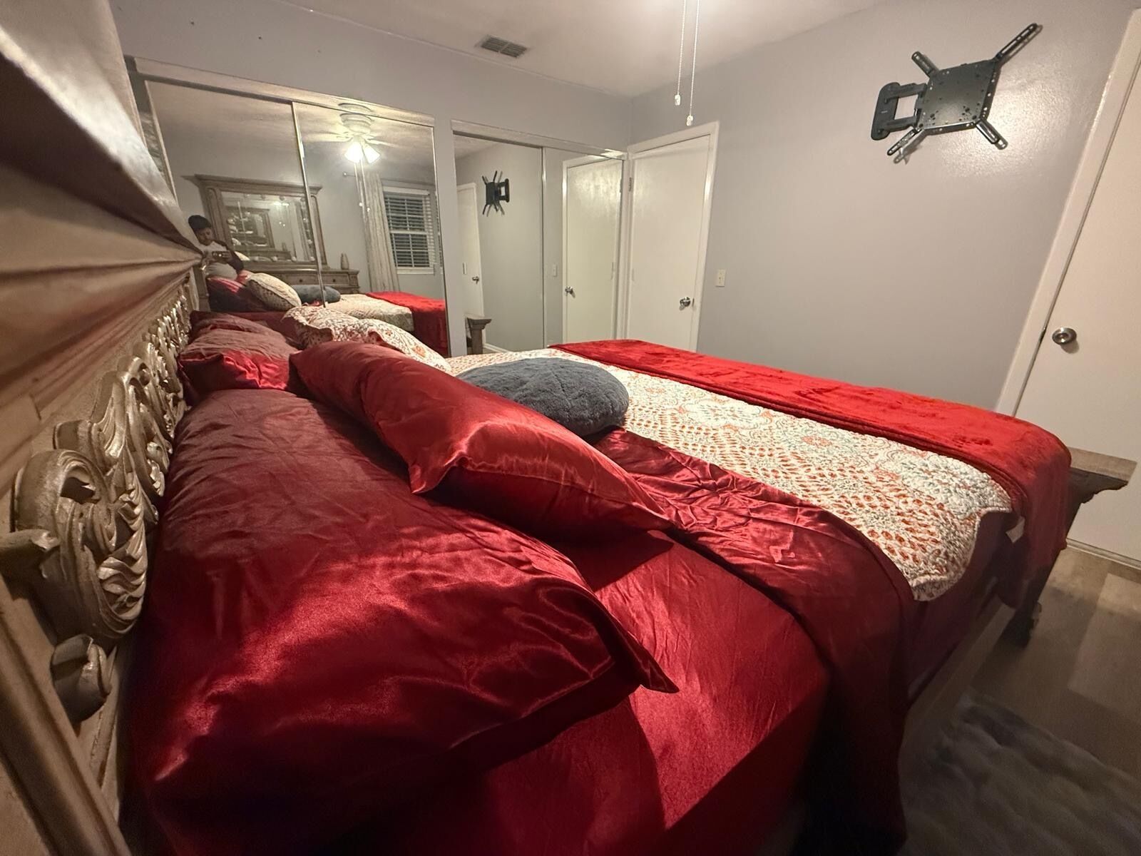 A bedroom with a large bed, a wardrobe, and a mirror.