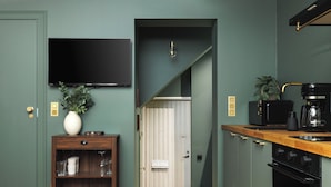 A kitchen with a wooden countertop, a coffee maker, and a television mounted above the door.