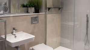 Un baño moderno con ducha acristalada, lavamanos blanco y retrete.