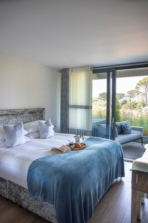 A bedroom with a large bed, a sofa, and a view of the outdoors. - Liner Apartment 7 (Falmouth)