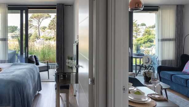 Una habitación de hotel moderna con balcón, zona de comedor y vistas al exterior.