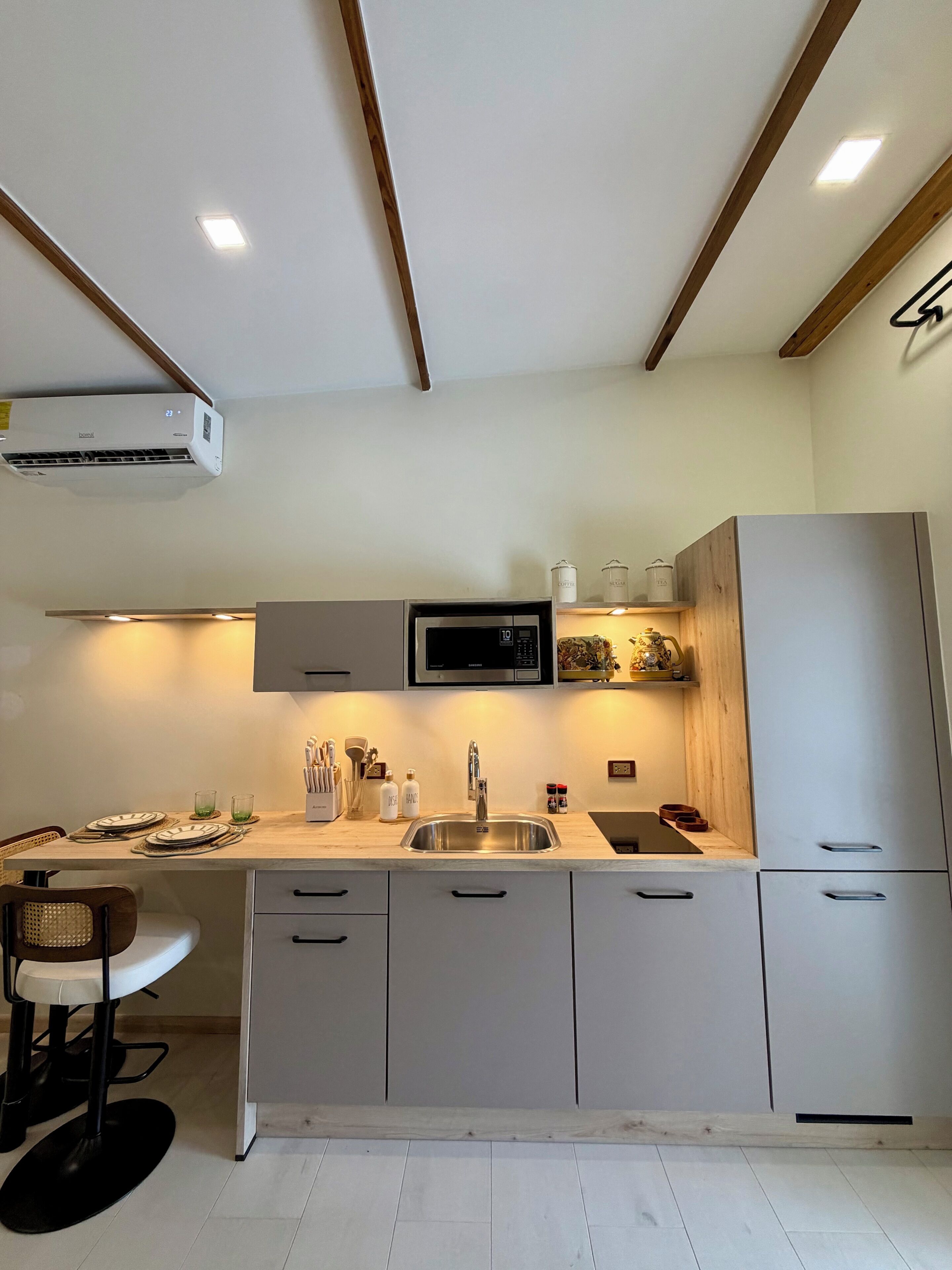 A modern kitchen with a built-in microwave, stainless steel sink, and wooden cabinets.