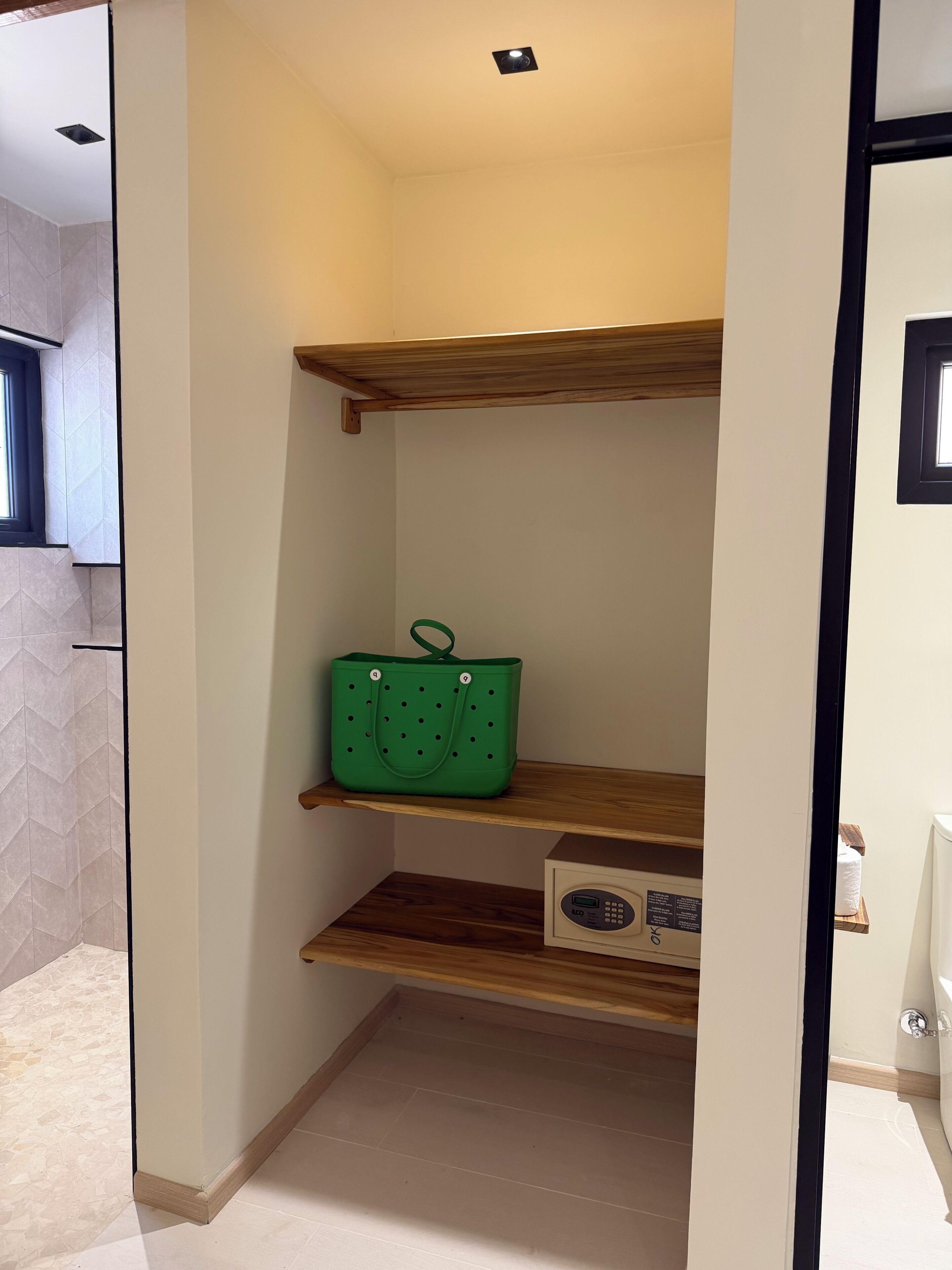 A hallway with a green bag on a shelf, a control panel, and a window.