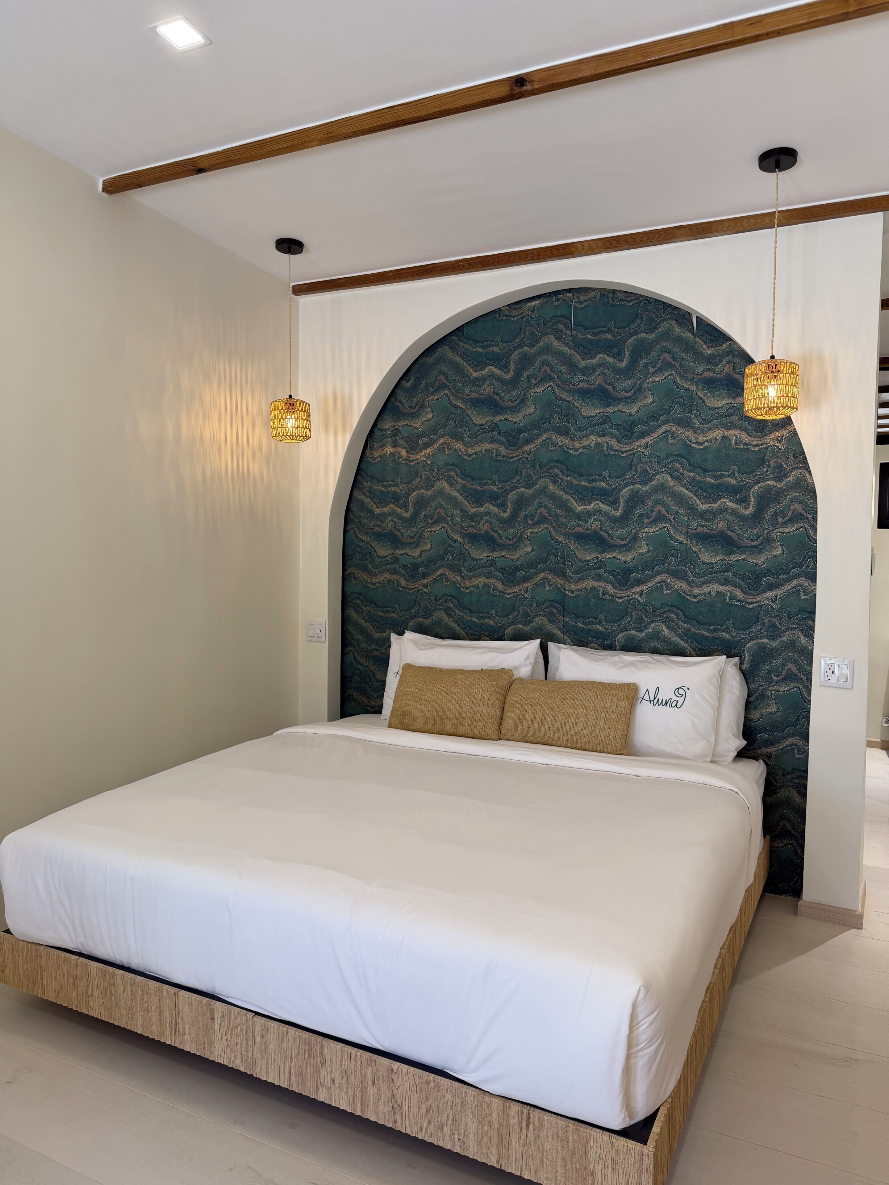 Ein modernes Schlafzimmer mit einem großen Bett, einer gewölbten Kopfteil und zwei Pendelleuchten.