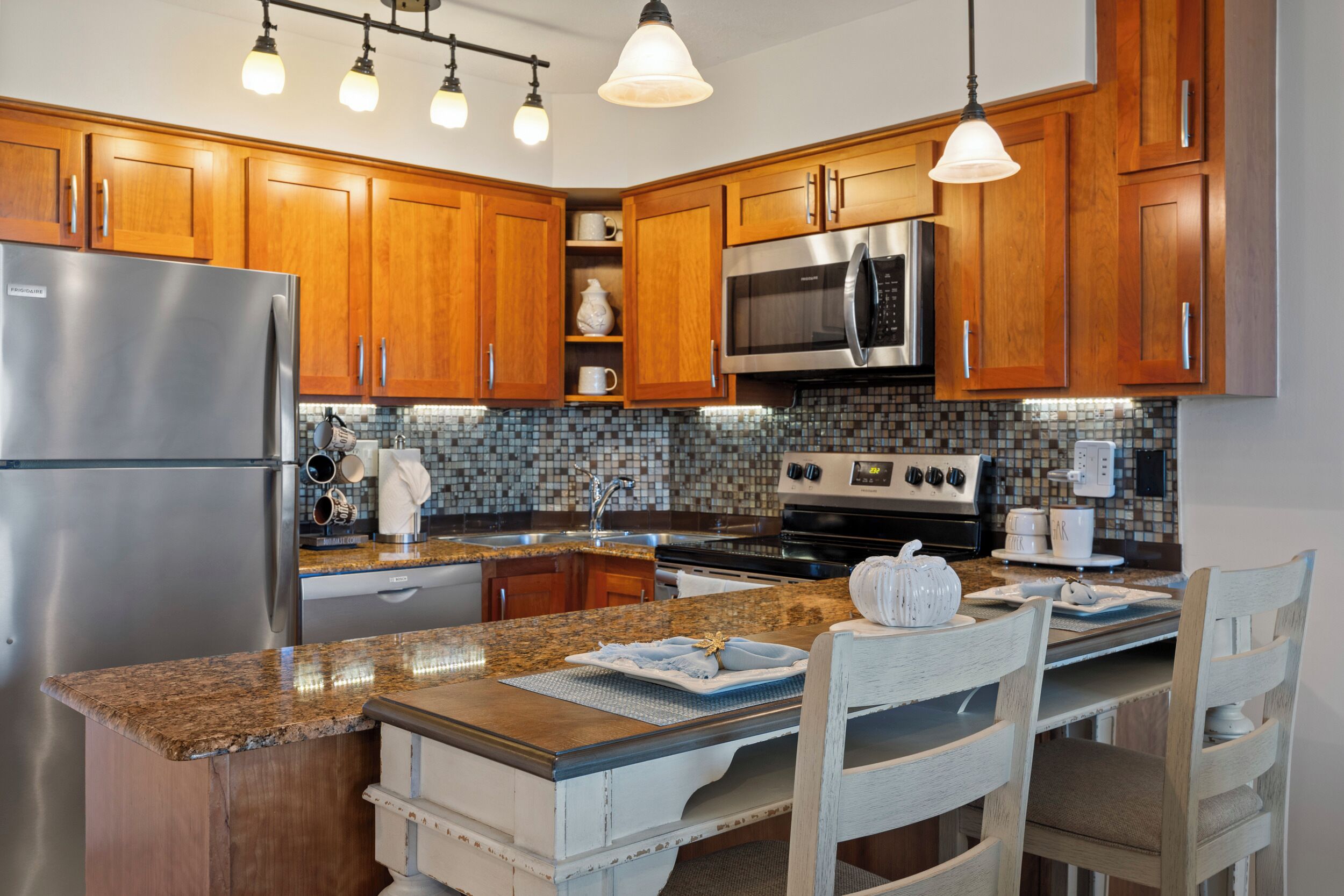 A modern kitchen with wooden cabinets, stainless steel appliances, and a granite countertop.