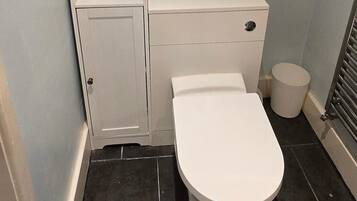 A bathroom with a toilet, a small cabinet, and a radiator.