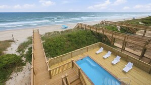 A wooden deck with a pool, lounge chairs, and a view of the beach and ocean. - Tide & Blue | Oceanfront Luxury, Pool, Sleeps 18 (Surf City)