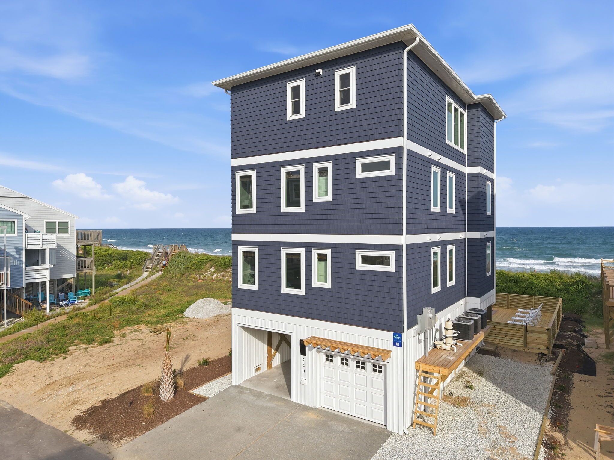 Ein mehrstöckiges Gebäude mit Garage in Strandnähe mit Blick aufs Meer.