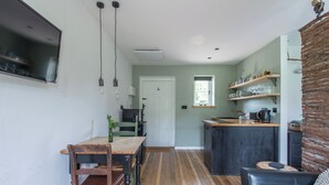 Cozinha moderna com mesa de jantar de madeira, bancada e área de estar com sofá de couro.