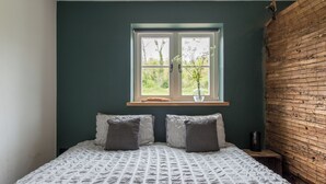 Une chambre à coucher avec un lit, deux oreillers, une fenêtre donnant sur un beau paysage et un mur en bois.
