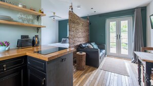 Une cuisine moderne avec des étagères en bois, un plan de travail noir et un mur d’accent en briques.