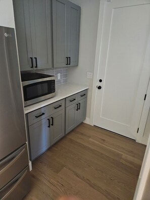 Una cocina compacta con gabinetes grises, un microondas y un refrigerador.