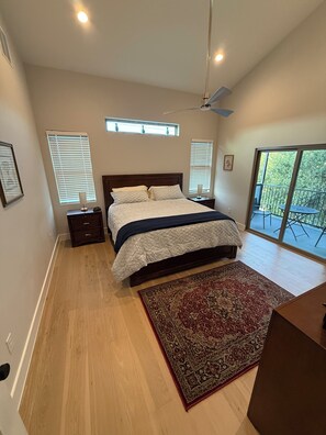 Ein Schlafzimmer mit einem Bett, einem Nachttisch, einem Schreibtisch, einem Sessel und einem großen Fenster mit Blick.