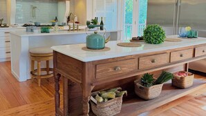 A modern kitchen with a large island, wooden flooring, and pendant lighting. - Private 16-Acre Lakefront Manor | Pool | Sleeps 14 (Culpeper)