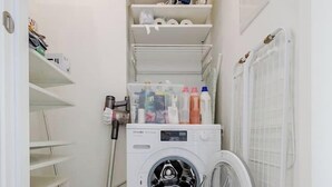 A laundry room with a washing machine, shelves with laundry supplies, and a vacuum cleaner. - lux Rooftop with A/C - Schönbrunn & Central Vienna (Wien)
