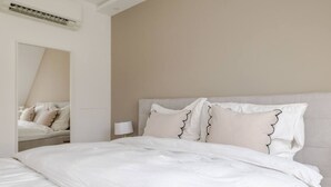 A neatly made bed with white bedding and decorative pillows, a bedside lamp, and a mirror reflecting the bed. - lux Rooftop with A/C - Schönbrunn & Central Vienna (Wien)