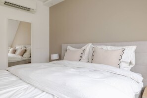 A neatly made bed with white bedding and decorative pillows, a bedside lamp, and a mirror reflecting the bed. - lux Rooftop with A/C - Schönbrunn & Central Vienna (Wien)