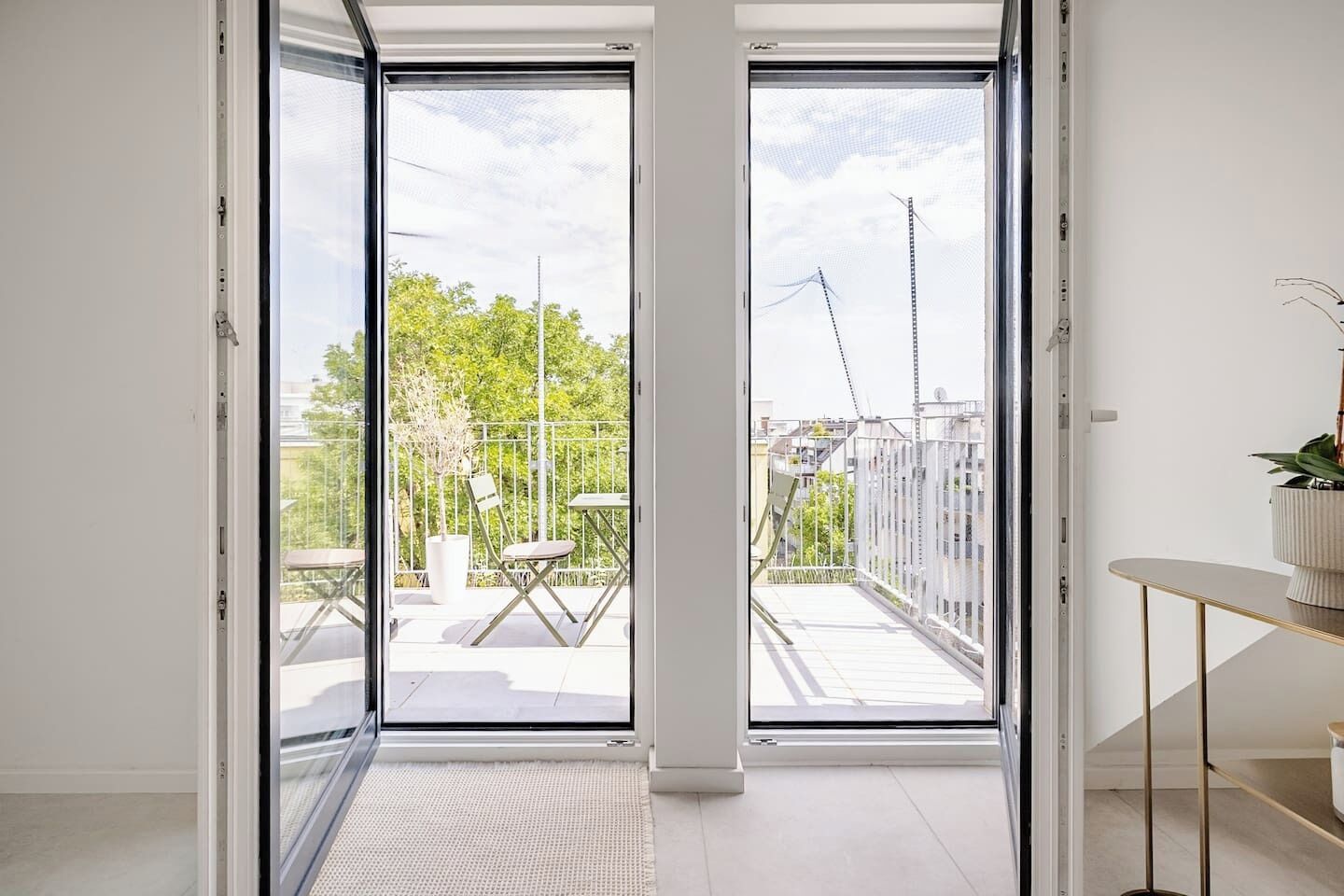 A modern interior with a sliding glass door leading to an outdoor balcony with a table and chairs.