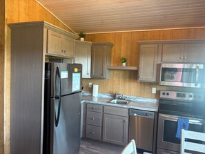 A modern kitchen with stainless steel appliances, wooden cabinets, and a countertop.