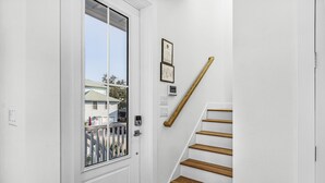 Ein helles Interieur mit einer Holztreppe, einer Tür mit Fenster und zwei gerahmten Zertifikaten an der Wand.