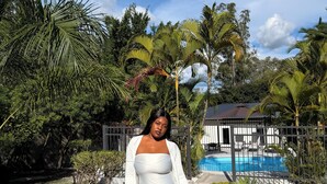 A person walking on a pathway surrounded by lush greenery and a swimming pool. -     Escape Ordinary at The Hill Manor - A Sanctuary of Luxury, Privacy & Comfort (Ndola)