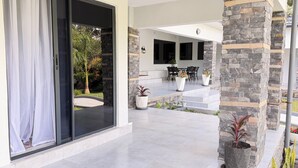 A modern house with a glass door, a patio with outdoor furniture, and a stone wall. -     Escape Ordinary at The Hill Manor - A Sanctuary of Luxury, Privacy & Comfort (Ndola)
