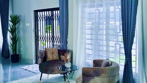 A spacious living room with a large window, a round coffee table, and a sofa. -     Escape Ordinary at The Hill Manor - A Sanctuary of Luxury, Privacy & Comfort (Ndola)