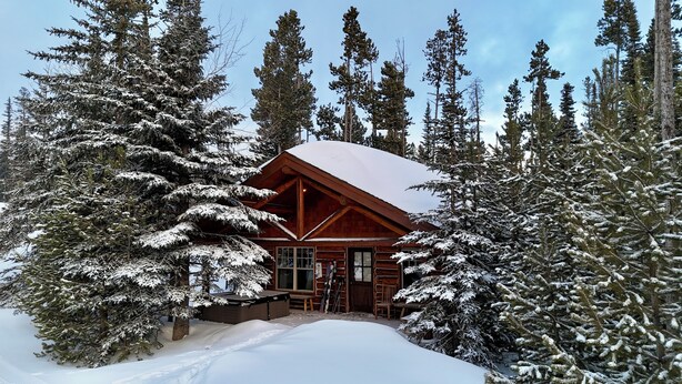 Una cabaña de madera rodeada de árboles cubiertos de nieve.