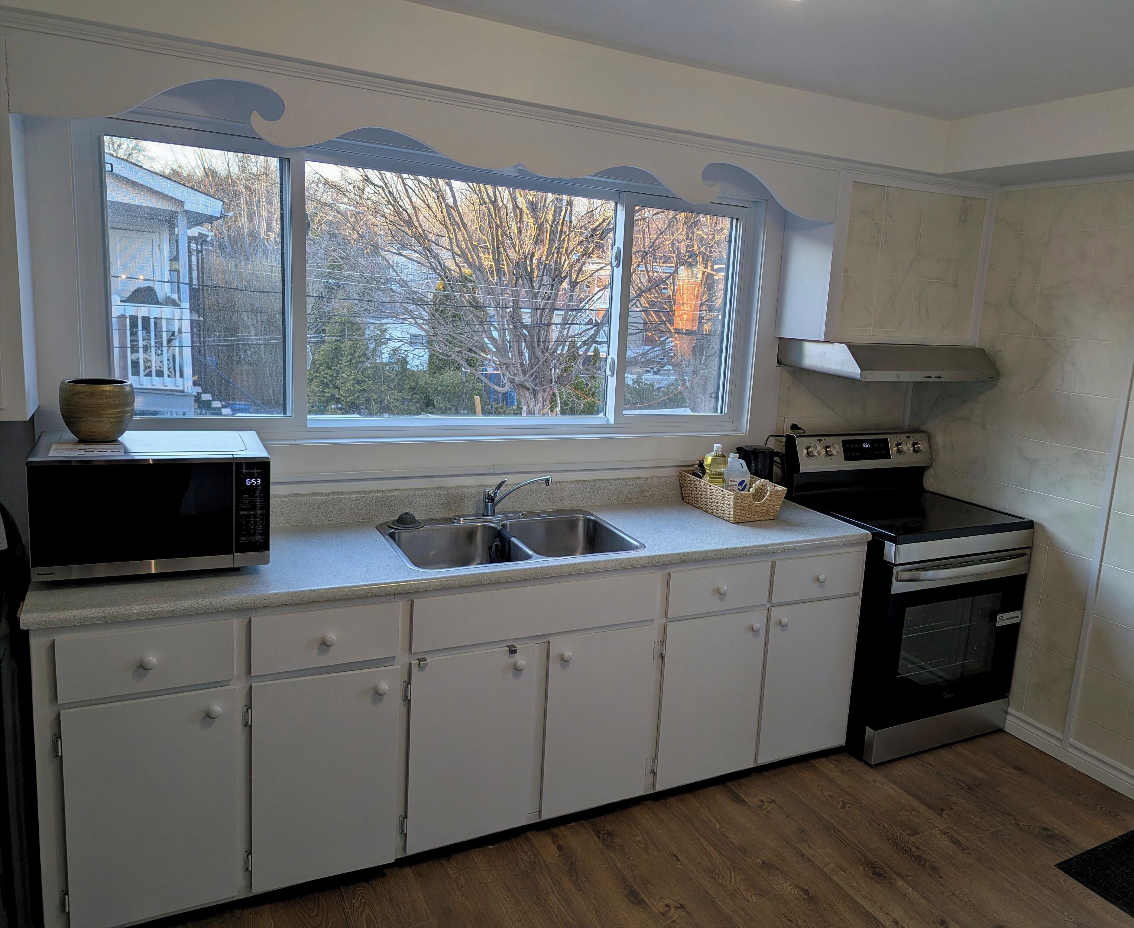 A kitchen with a microwave, stove, sink, and cabinets.