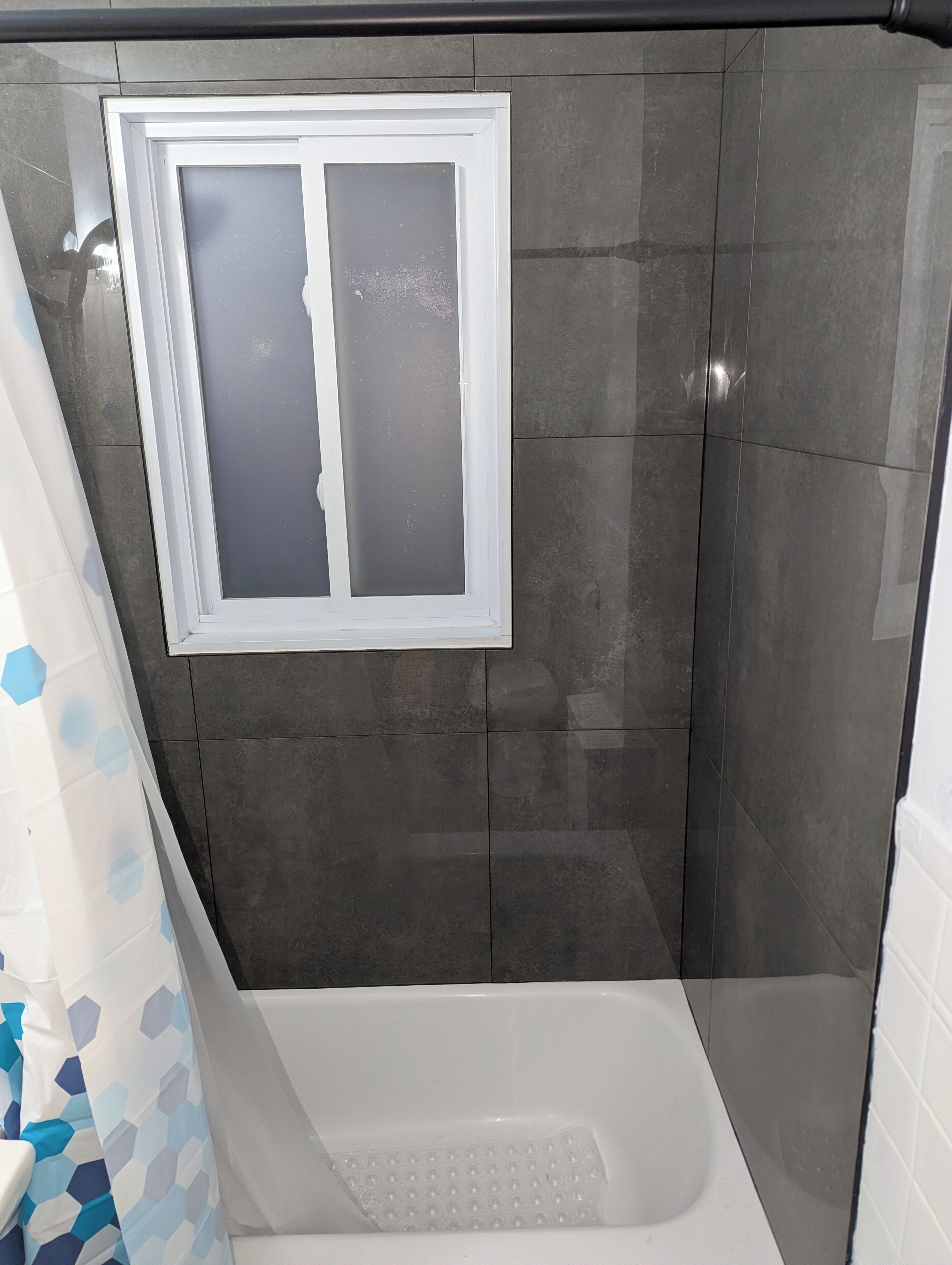 Une salle de bain avec une douche, une fenêtre et une baignoire.