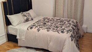 Une chambre à coucher avec un lit, un ventilateur de plafond et une fenêtre avec des rideaux.