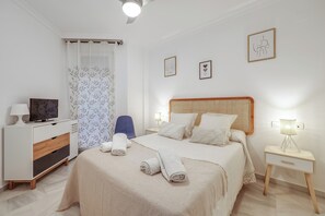A hotel room with a bed, a desk, a chair, a TV, and a nightstand with a lamp. - LXR Esmeralda 2-Bedroom Near the Ocean (Fuengirola)