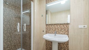 A bathroom with a glass shower enclosure, a white sink, and a tiled backsplash. - LXR Esmeralda 2-Bedroom Near the Ocean (Fuengirola)