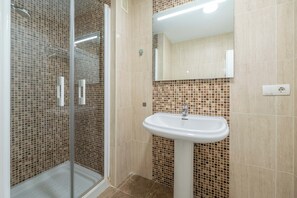 A bathroom with a glass shower enclosure, a white sink, and a tiled backsplash. - LXR Esmeralda 2-Bedroom Near the Ocean (Fuengirola)