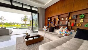 A modern living room with a large sofa, a coffee table, and a bookshelf. - Villa D'horizon (Marrakech)