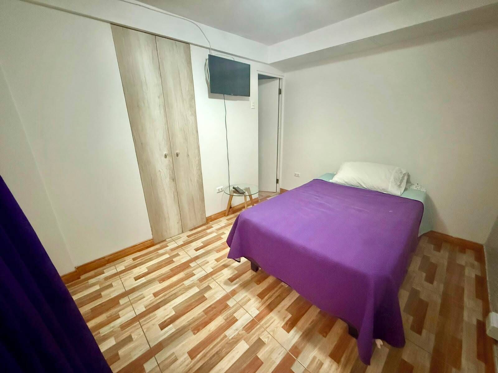 A bedroom with a bed, a wardrobe, and a television.