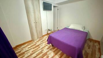 A bedroom with a bed, a wardrobe, and a television.