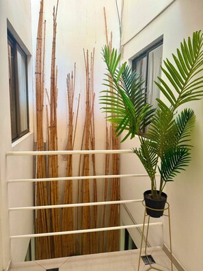 Habitació amb paret de bambú, una planta en test i una barana blanca.