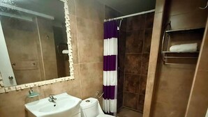 Un baño con lavamanos, inodoro y ducha.