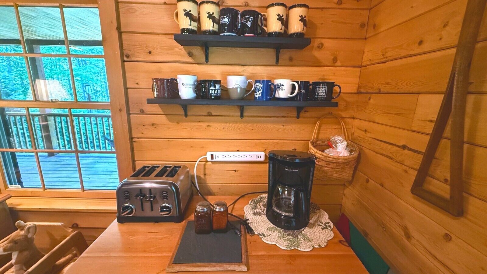 Eine Küchenzeile mit Toaster, Kaffeemaschine und Regalen mit Tassen.