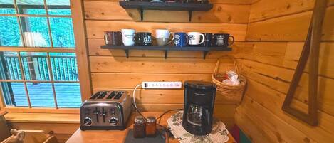 Eine Küchenzeile mit Toaster, Kaffeemaschine und Regalen mit Tassen.