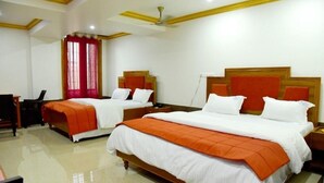 A hotel room with two beds, a desk, and a ceiling fan. - Hotel Chembiyan (Pudukkottai)