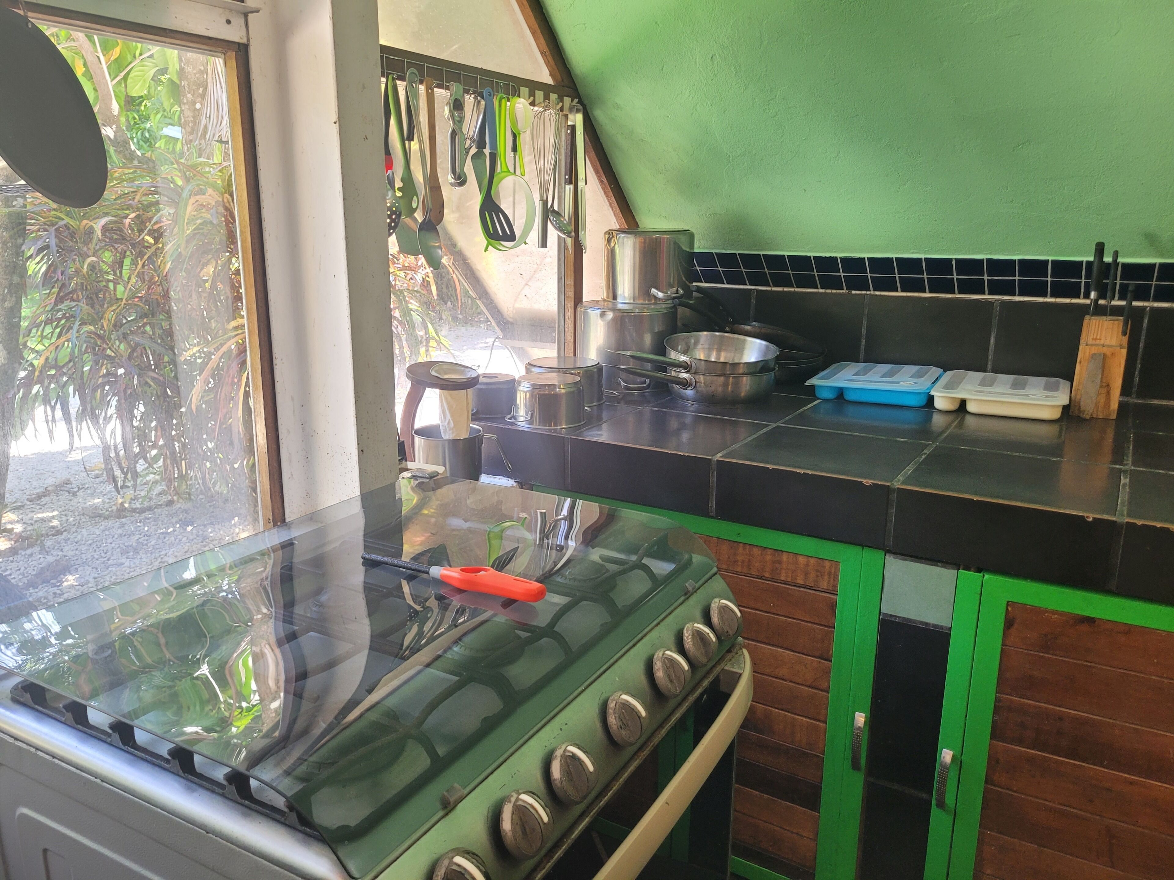 A kitchen with a stove, pots, pans, and utensils.