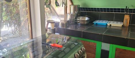 A kitchen with a stove, pots, pans, and utensils.
