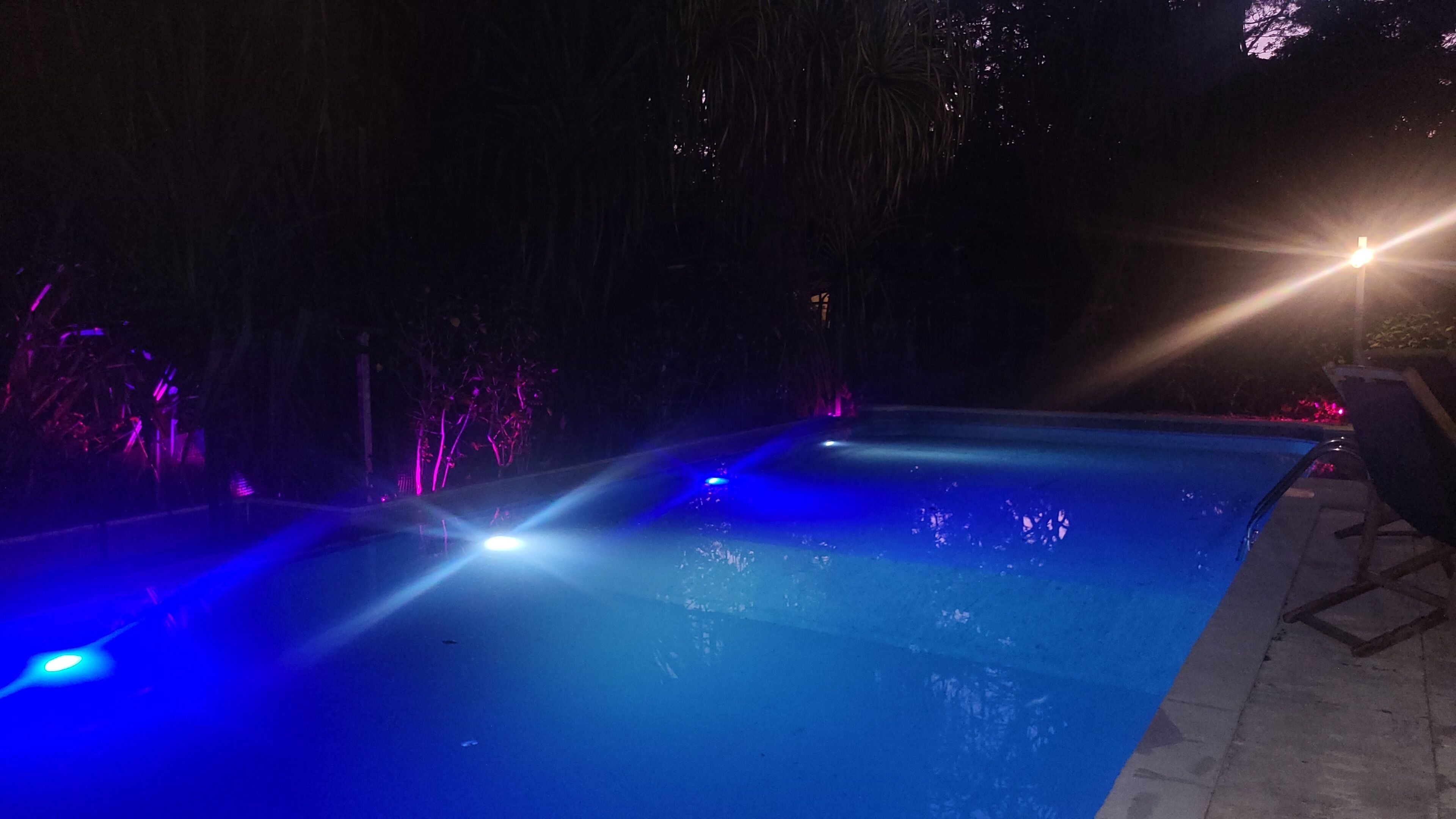 Une piscine dotée d’un éclairage bleu et d’un espace patio.