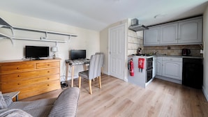 A compact living space with a kitchenette, a dining area with a table and chairs, a television, and a sofa. - Studio Retreat Sleeps 1 - Wifi & Parking (Cambridge)