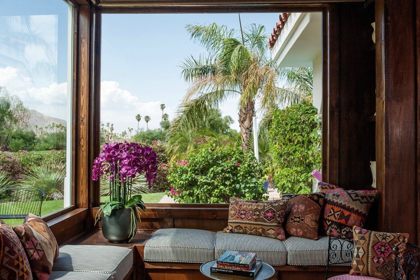 Un espacio de descanso acogedor con vistas a un jardín exuberante y palmeras.