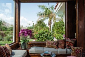 A cozy seating area with a view of a lush garden and palm trees. - Indian Canyons Golf Resort Fairway-Front Home Pool & Spa + Golf & Mountain Views (Palm Springs)